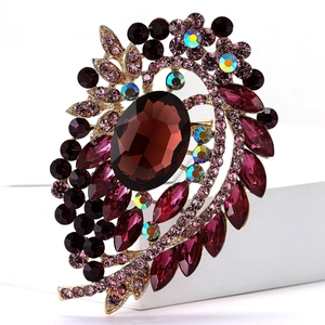 Detailed close-up of a vintage golden alloy brooch with red and purple rhinestones