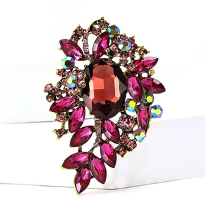 Detalle de broche vintage con piedras rojas y cristales rosa sobre base dorada