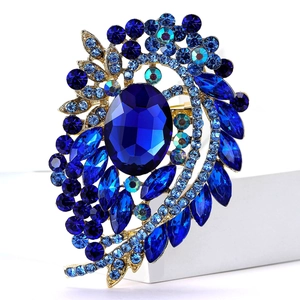 Macro detail of high-end vintage gold brooch with blue crystals and large oval gemstone