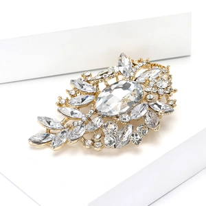 Vista macro del broche dorado con cristal ovalado y brillantes diamantes de imitación