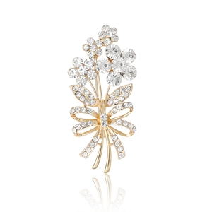 Elegant gold plated floral brooch with rhinestones and ribbon bow on white background