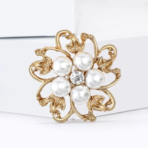 Broche fleur dorée élégante avec perles blanches et strass sur un piédestal blanc