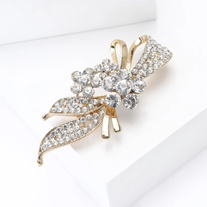 Détail d'une broche fleurie dorée ornée de strass brillants avec ruban élégant