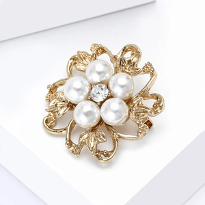 Détail d'une broche fleur avec perles blanches et strass sur base en alliage doré
