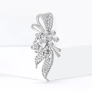 Élégante broche fleur et nœud argentée avec strass scintillants sur support épuré