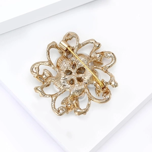 Broche fleur dorée évidée avec épingle de sûreté sur plateforme géométrique blanche
