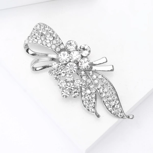 Détail d'une élégante broche fleur argentée avec strass cristallins et rubans courbés
