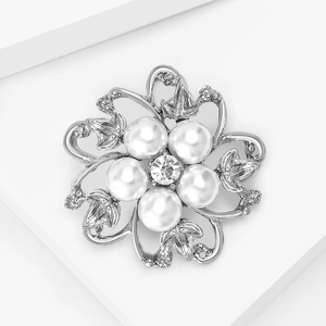 Gros plan d'une broche fleur argentée vintage avec perles blanches et cristal étincelant