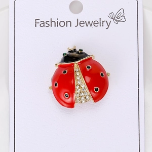 Détail de la broche coccinelle rouge avec strass brillants sur une base en alliage doré