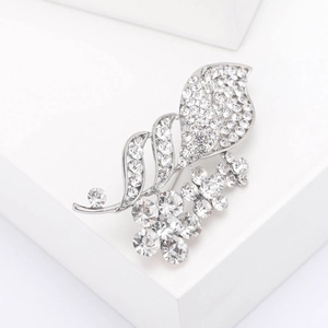 Detail view of silver flower brooch featuring crystal rhinestones on a white pedestal