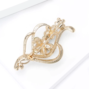 Détail du dos de la broche fleur dorée montrant les motifs de cœur et le fermoir à épingle