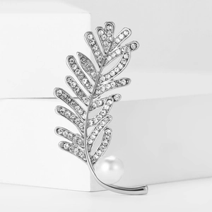 Détails d'une broche plume argentée avec strass scintillants et perle blanche élégante