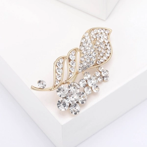Detailed view of floral rhinestone brooch with gold plating on minimalist white background