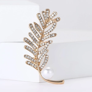 Élégante broche plume dorée avec cristaux et perle sur fond blanc géométrique