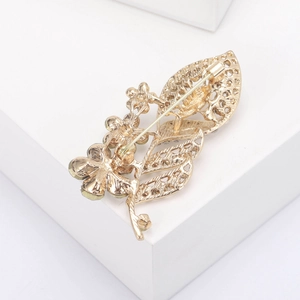 Detail view of the back of gold leaf brooch showing safety pin and hollow metal craft