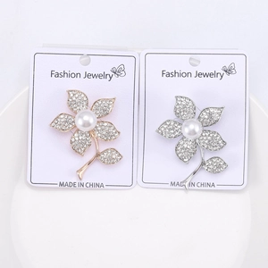 Gros plan de broches fleur en perles et strass dorées et argentées sur carte de vente