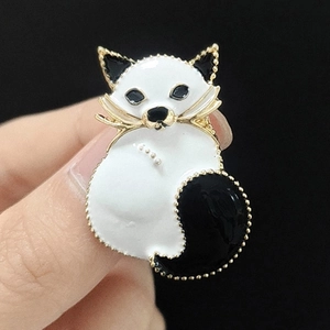 Macro detail of enamel cat brooch with white and black glaze and gold-plated textured edges