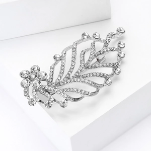 Detail view of silver rhinestone leaf brooch on a white geometric display stand