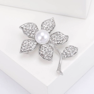 Gros plan détaillé d'une broche fleur argentée avec strass blancs et perle centrale
