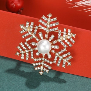 Elegant gold snowflake brooch with central pearl and white rhinestones on festive background