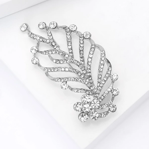 Macro shot of silver feather brooch with sparkling zircons and floral detail on white pedestal