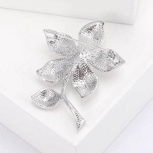 Détail macro du dos d'une broche fleurie en argent avec fermoir à aiguille sur blanc