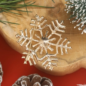 Elegant gold snowflake brooch with pearls and rhinestones on festive holiday background