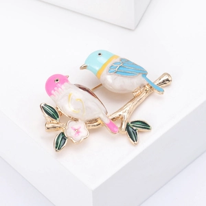 Detailed close-up of colorful enamel bird brooch with green leaves on gold branch