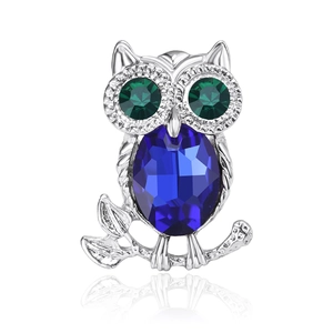 Macro detail of owl brooch with deep blue faceted gemstone body and green eyes