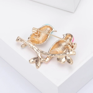 Golden double bird brooch with safe pin closure and delicate matte metal texture