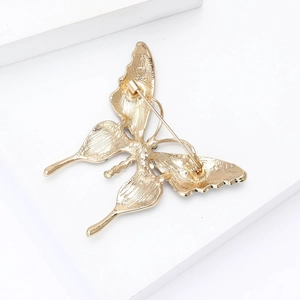 Broche papillon dorée avec strass et émail montrant la structure arrière et l'épingle