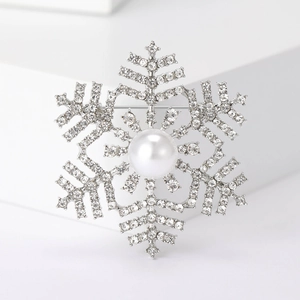 Detailed close-up of a silver snowflake brooch with sparkling rhinestones and center pearl