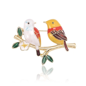 Détail de la broche oiseau en émail avec plumes colorées sur une branche dorée fleurie