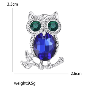 Detailed owl brooch featuring blue crystal body, green stone eyes, and silver-tone metal finish