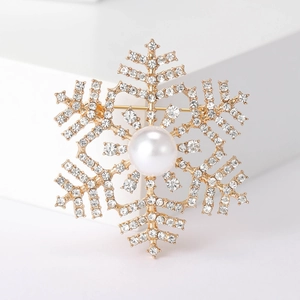 Macro shot of gold snowflake brooch with sparkling rhinestones and a central pearl detail