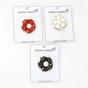 Detalle de broches de flores de aleación con perlas en colores rojo, blanco y negro
