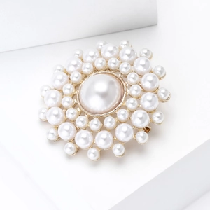Détail macro d'une broche en perles de luxe avec une grande perle centrale et métal doré