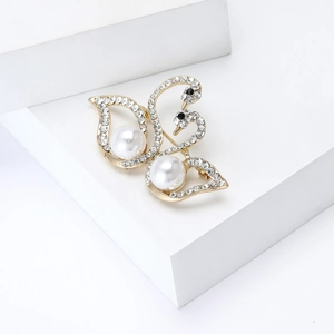 Macro detail of elegant double swan brooch with white pearls and sparkling rhinestones