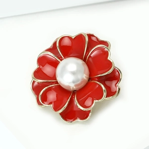 Detalle de broche elegante con pétalos de corazón rojos y una gran perla blanca central