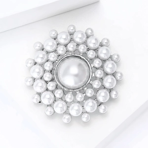 Gros plan d'une broche ronde minimaliste ornée de perles blanches sur un support argenté