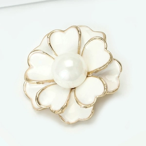Vista detallada del broche de camelia con pétalos de esmalte blanco y perla central