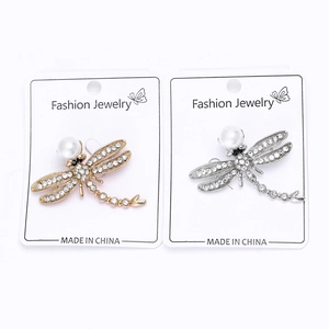 Macro detail of gold and silver dragonfly brooches with pearls and sparkling crystals