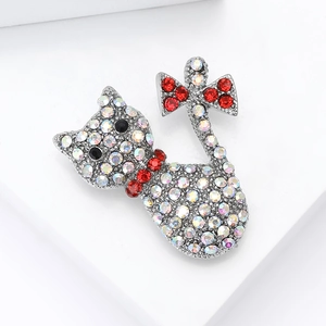 Close-up of cat brooch with silver base and colorful rhinestones featuring red bow details