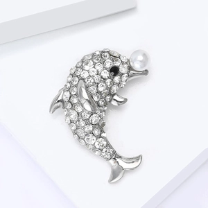 Broche dauphin argentée avec cristaux étincelants et perle blanche sur fond blanc pur