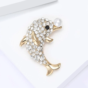 Élégante broche dauphin dorée avec strass blancs et perle sur un socle blanc épuré