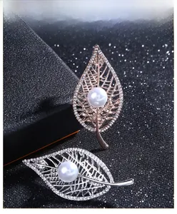 Close-up of hollow leaf brooch with sparkling crystals and a white round pearl