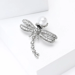 Detailed view of silver dragonfly brooch with white pearls and sparkling rhinestones