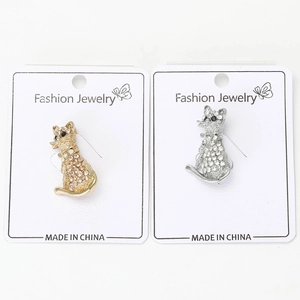 Détail de broches chat mignon en or et argent avec strass scintillants sur carte de bijoux