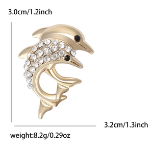 Broche dauphin dorée avec strass scintillants et yeux en gemmes noires sur fond blanc