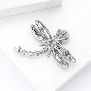 Detailed view of silver dragonfly brooch back with secure pin clasp and round white pearl